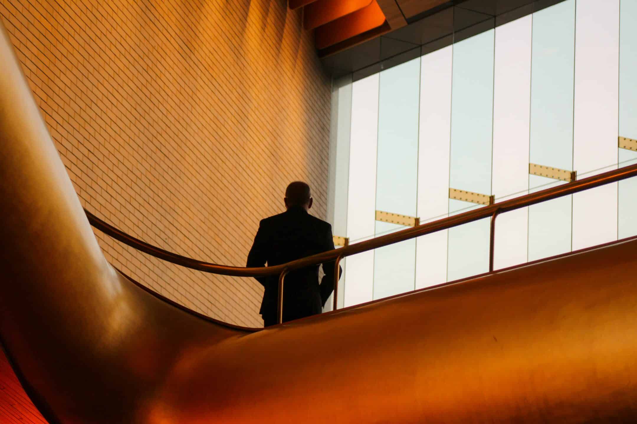 man standing on upper level of a building looking out windows