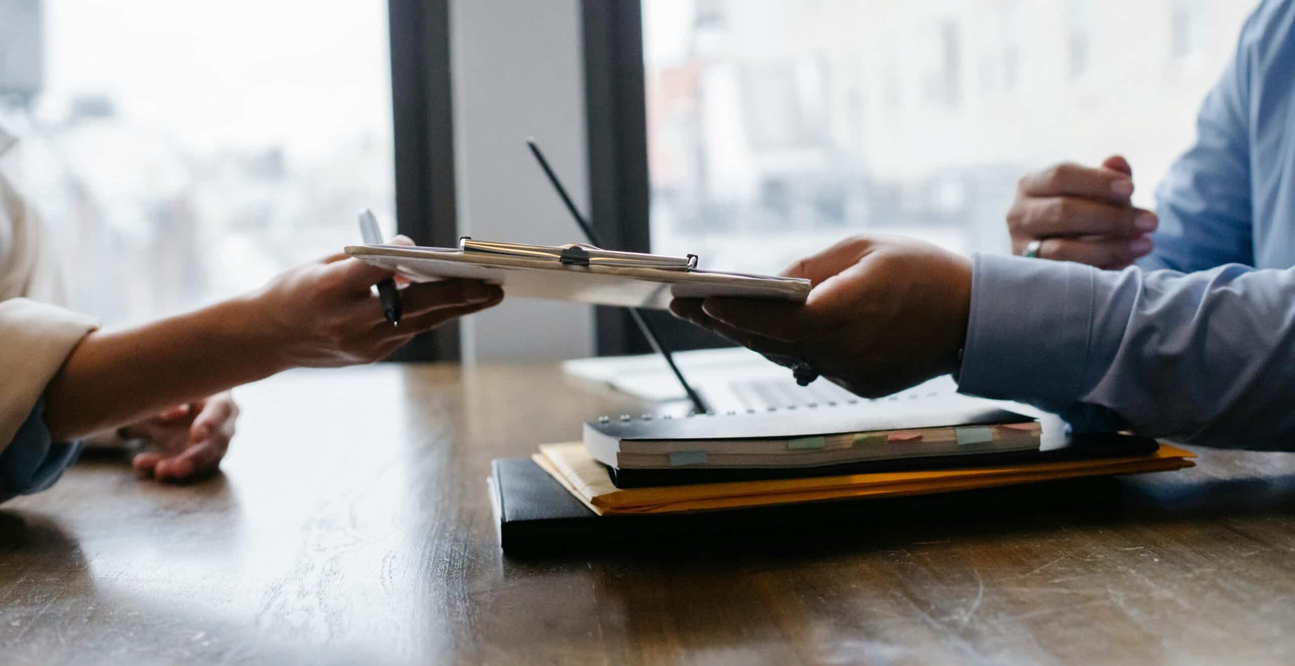 Person passing a folder in an office representing temporary layoffs versus constructive dismissal and its differences.