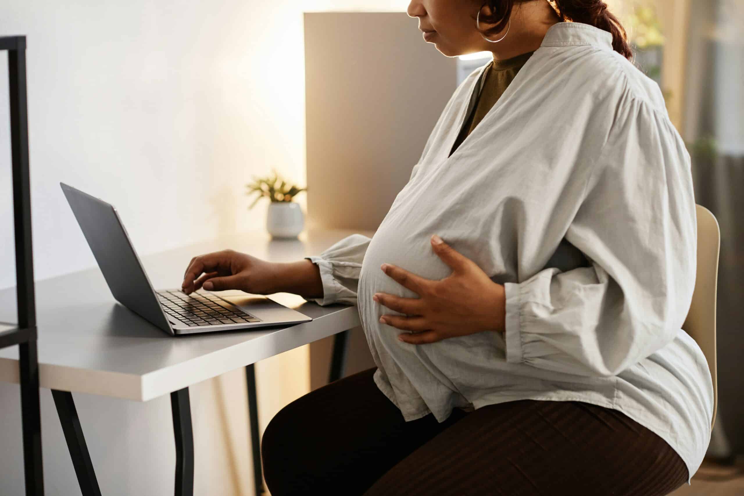 Pregnant woman in front of laptop representing pregnancy discrimination in the workplace